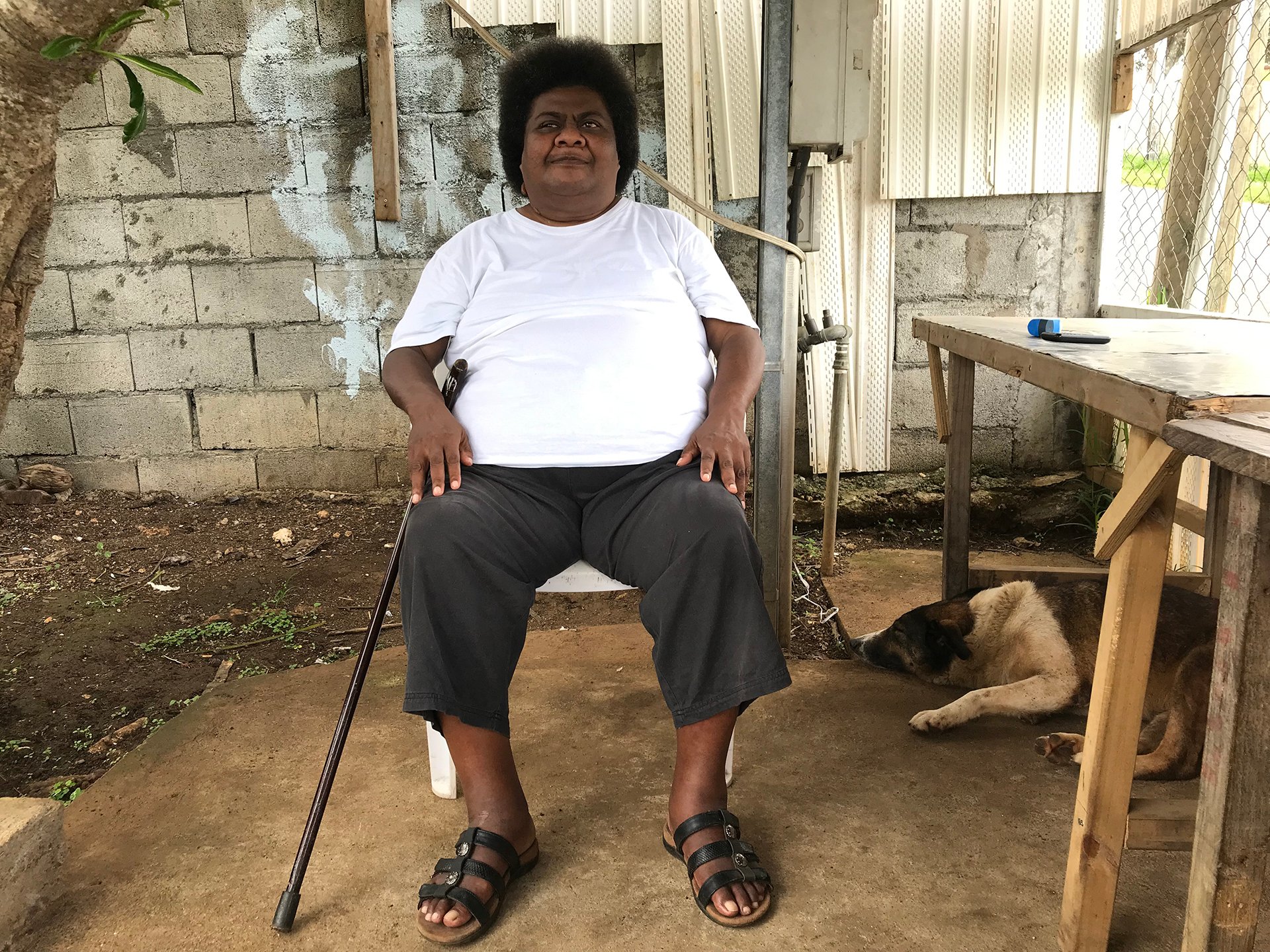 person sitting on a chair holding a walking stick